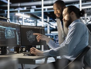 Team of technicians using PC in data center, integrating AI driven automation tools, doing maintenance. Server farm coworkers using artificial intelligence machine learning models